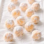 Orange Creamsicle Truffles stacked on a white marble plate