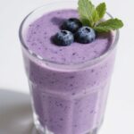 Blueberry Coconut Smoothie in a glass topped with blueberries and coconut flakes
