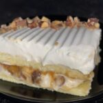 A close-up of a sliced Almond Caramel Layer Cake showcasing its golden sponge, caramel whipped cream, and toasted almonds.