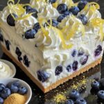 No-Bake Lemon Blueberry Cream Cake with a buttery graham cracker crust and a creamy lemon filling, topped with fresh blueberries.