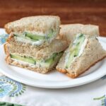 Cucumber sandwiches on a plate with garnish, served for tea.