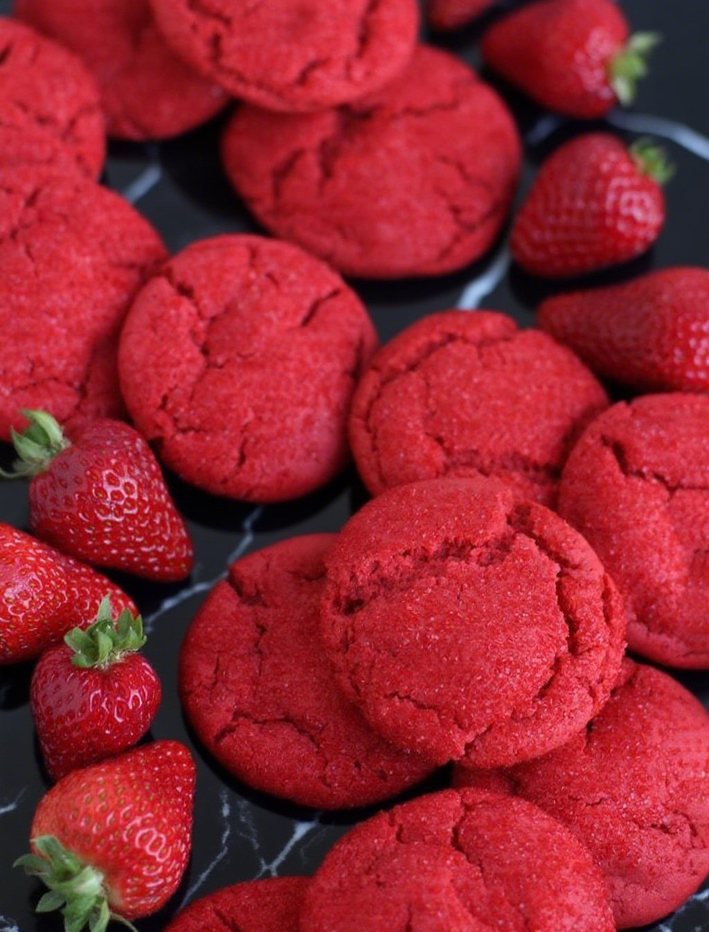 Strawberry sugar cookie with a cracked red surface, dusted with sparkling sugar